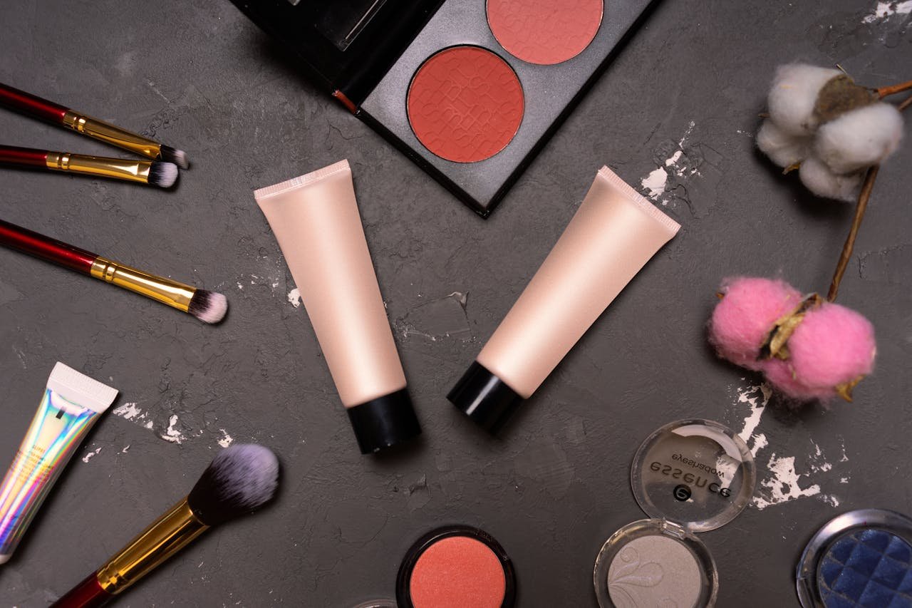 services-03 A stylish flat lay showcasing cosmetics including brushes and creams on a dark background.