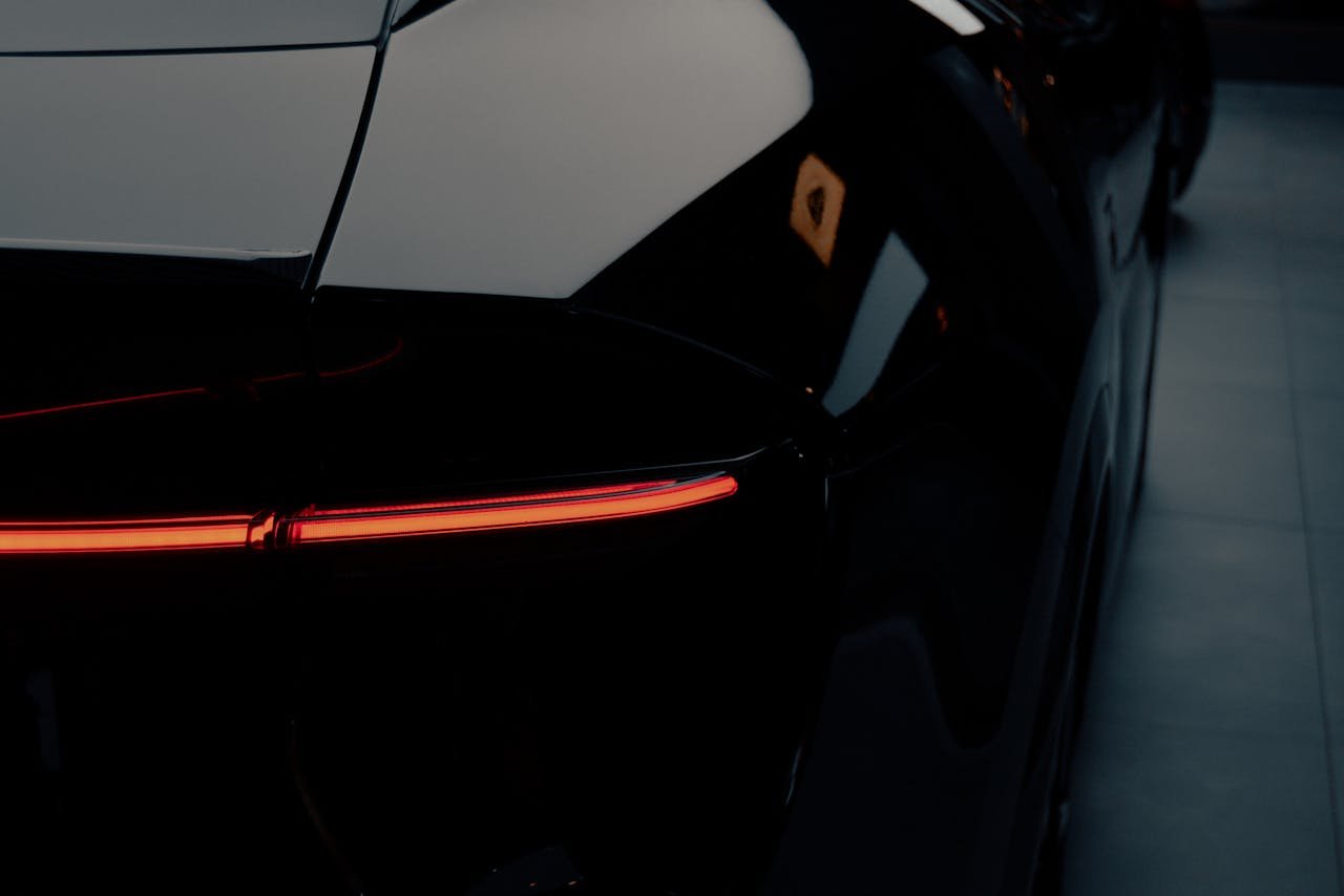 A close-up shot of a sleek black sports car featuring its striking red tail light design.